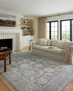 a living room filled with furniture and a large rug on top of a hard wood floor