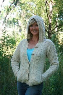 a woman standing in the grass wearing a cardigan and smiling at the camera with her hands on her hips