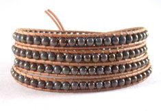 Leather wraps are a great way to add a fun, boho, chic look to any outfit.  They can be worn alone or with a bangle or another wrap for an interesting cluttered look.  The 4 mm bluish, lavender with  bronze glaze Czech glass beads, are nestled between natural Greek leather cording.  A delightful, textured, copper button finishes the look.  The bracelet is threaded twice for additional strength and durability.  It measures 32- 1/2" for a loose, comfortable fit for most size 7 - 7 1/2" wrists. This bracelet will arrive ready for gifting. I ship USPS first class.  I include delivery confirmation, when available, at no extra cost to you.  I will supply you with a tracking number.  For additional information on shipping, please see my shop policy page. I welcome all questions!  Thank you for yo Brown Hand Wrapped Beaded Bracelets For Festivals, Hand Wrapped Brown Beaded Bracelets For Festivals, Brown Beaded Wrap Bracelet For Festival, Bohemian Wrap Bracelet With Black Beads For Gift, Bohemian Black Beads Wrap Bracelet Gift, Bohemian Black Beads Adjustable Wrap Bracelet, Bohemian Adjustable Black Beads Wrap Bracelet, Beaded Brown Wrap Bracelet For The Beach, Beaded Brown Wrap Bracelet For Beach