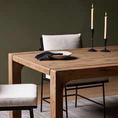 a wooden table with two chairs and a plate on top of it next to candles