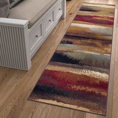 a living room with a couch and rugs on the wooden floor next to a window