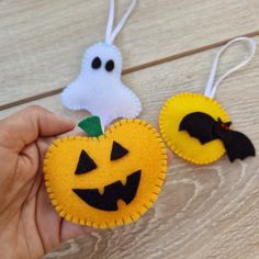 two felt pumpkins with bats on them and one has a ghost hanging from it