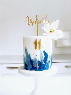 a white and blue cake with gold numbers on it