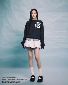 a young woman is standing in front of a blue background wearing a black sweater with white flowers on it