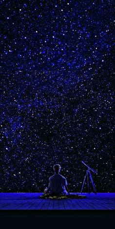 a man sitting in the middle of a wooden floor under a night sky filled with stars