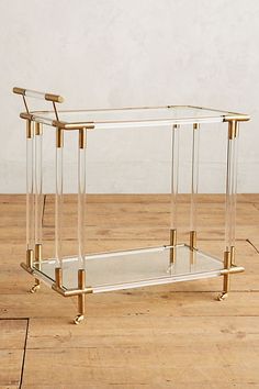 a glass and brass coffee table sitting on top of a wooden floor