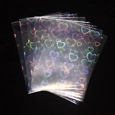 four clear heart shaped stickers on top of each other in front of a black background