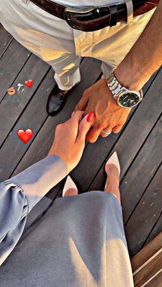 two people holding hands while sitting on a wooden deck with hearts scattered around them and the man is holding the woman's hand