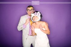 a man and woman posing for a photo in front of a purple wall with a hello kitty mask on