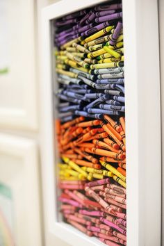 an image of colorful crayons in a white frame hanging on the side of a wall