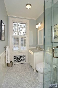 a bathroom with a toilet, sink and shower in it's own area next to a window