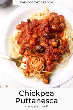 a white plate topped with pasta covered in sauce and garnished with chickpea