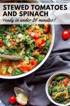 two bowls filled with stew and spinach on top of a blue towel next to tomatoes