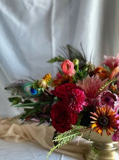 a vase filled with lots of colorful flowers on top of a white cloth covered table