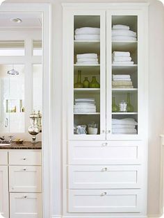 white linens are stacked on top of each other in a closet with glass doors