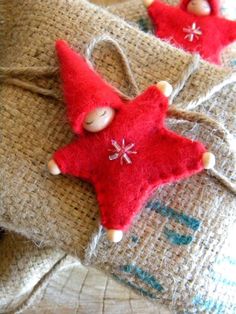 two red ornaments are sitting on some burlocked fabric, one is shaped like a star