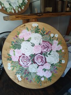 two mirrors with flowers painted on them in front of a table and fan, next to each other