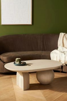 a white table sitting on top of a hard wood floor next to a brown couch