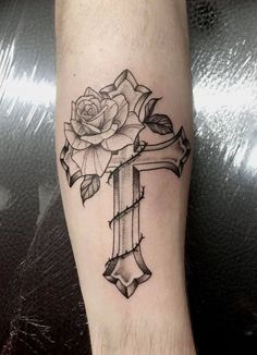 a cross with a rose tattoo on the arm and foot is shown in black ink