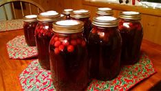 several jars filled with red berries sitting on top of a wooden table