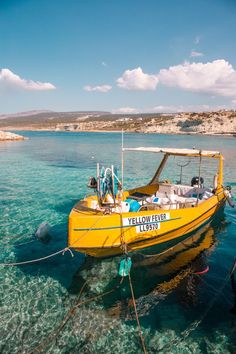 a small yellow boat floating on top of clear blue water