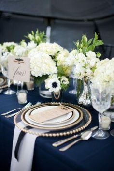 the table is set with white flowers and place settings