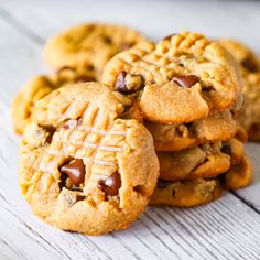 a pile of cookies sitting on top of a white wooden table covered in chocolate chips