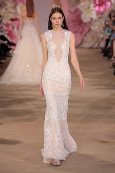 a model walks down the runway in a white gown with sheer cutouts on it