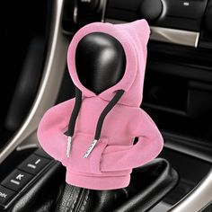 a pink hoodie sitting on top of a steering wheel in the center console of a car