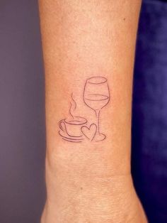 a small tattoo on the wrist of a woman with a cup and saucer in it