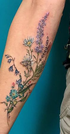 a woman's arm with flowers on it and a butterfly in the middle of her arm