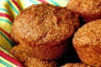 some muffins are sitting in a bowl on a tablecloth with a striped napkin