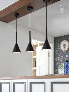 three lights hanging from the ceiling in a kitchen