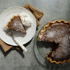 a piece of pie on a plate next to a fork and napkin with whipped cream