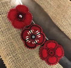 two red beaded flowers sitting on top of a table next to a pair of scissors