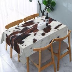 a table with two chairs and a cow print tablecloth on it in front of a window