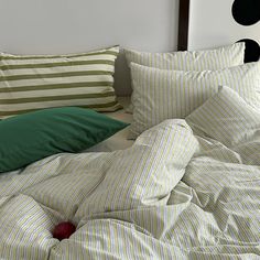 an unmade bed with green and white pillows