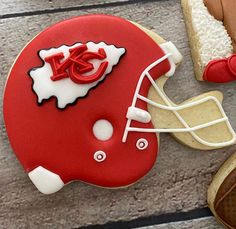 a decorated cookie with a football helmet on it next to cookies and other food items