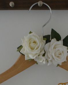 a wooden hanger with two white roses on it