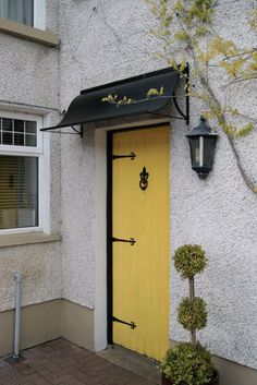 a yellow door is next to a potted plant on the side of a building