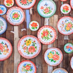 many colorful plates and bowls on a wooden table with flowers painted all over the surface