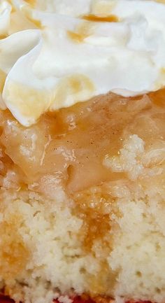 a piece of cake with whipped cream and caramel sauce on top is sitting on a red plate