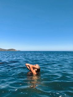 a woman is floating in the ocean with her head above the water's surface