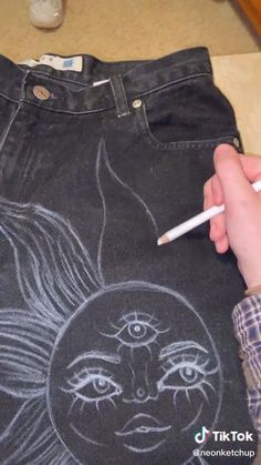 someone is drawing on the back of a jean pant with a white pencil and an image of a woman's face