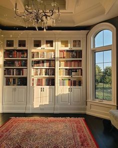 a living room filled with lots of books on top of a book shelf next to a window