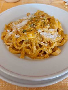 a white plate topped with pasta covered in sauce and parmesan sprinkles