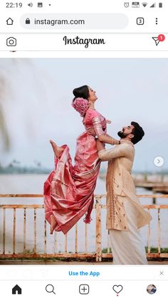 a man is holding a woman in his arms and she is wearing a pink dress