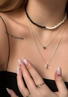 a woman with white nails and red nail polish holding her hand up to her chest