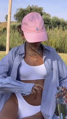 a woman wearing a pink hat sitting on a bench with a drink in her hand