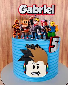 there is a blue cake with toy figures on it and the name gabril